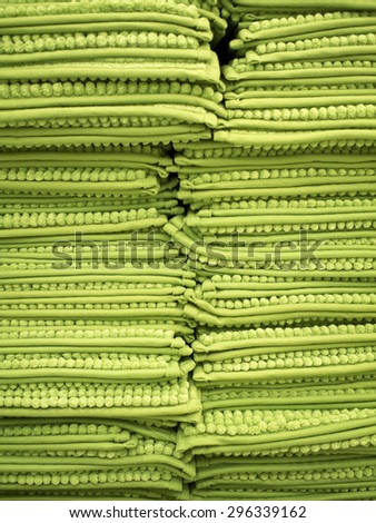 The close up picture of pile ,or stack, of all green rugs displayed in two column filled the whole frame. The result creates attractive look of texture.