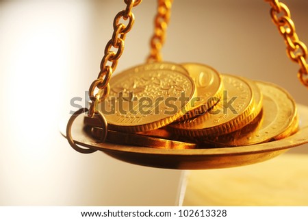 stacks of bright new shiny gold coins placed on weighing scales