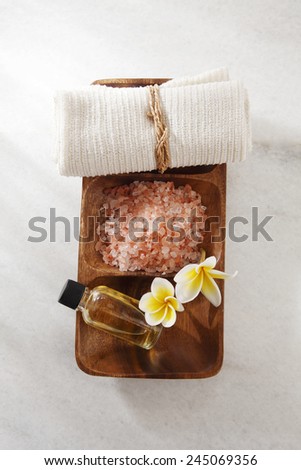 frangipani flower,salt,massage oil and towel in a wooden bowl