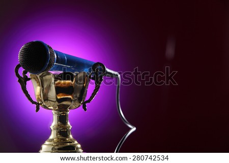 golden trophy  and microphone with purple background