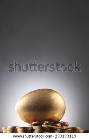 golden egg rest on stacks of coins