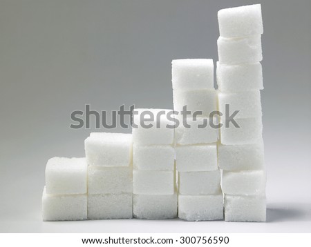 Ascending stacks of sugar cubes over gray background. This in a concept for high risk of diabetes or other diseases caused by excessive consumption of sugar