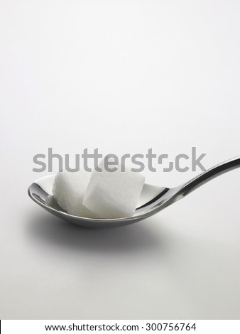 spoonful of sugar cubes on white