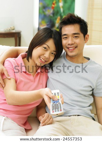 A young woman making funny faces while reaching out to get the remote controller