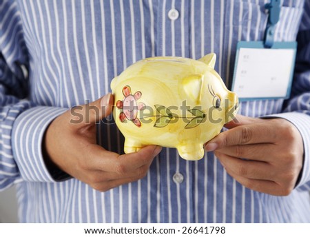 middle section of man holding piggy bank