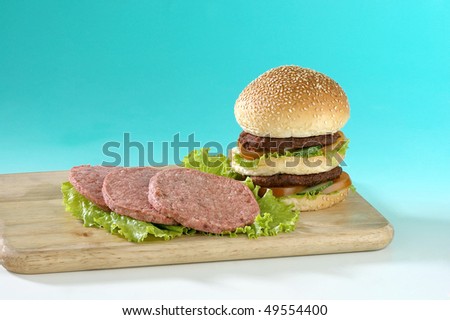 Three uncooked ground lamb patties with ready-to-eat burger.