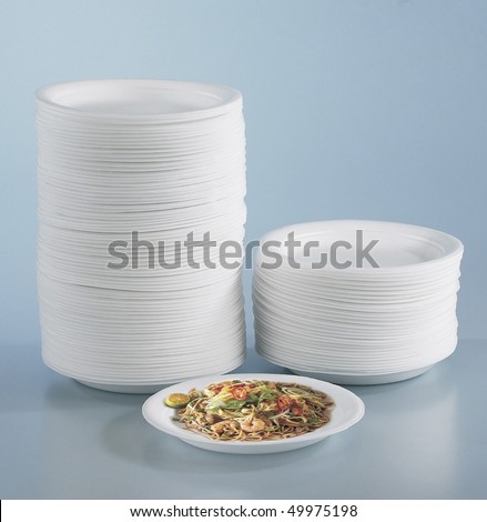 Stacks of round polystyrene plates and fried mee on a round plastic plate.