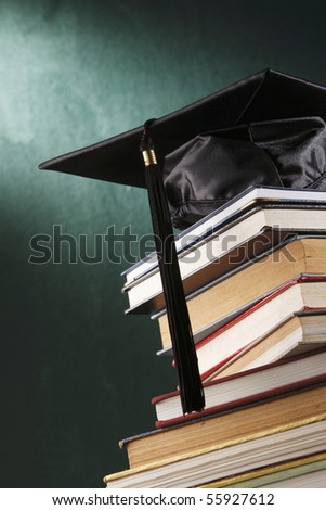 Graduation cap with book  in front of black board