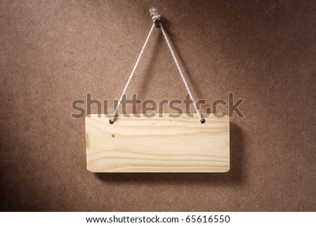 Empty wooden sign hung on background.