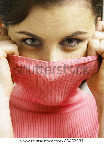 Woman covering face with turtleneck looking at the camera