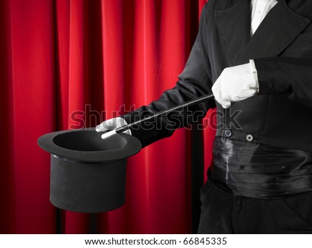 Hands of the magician with magic wand and top hat.