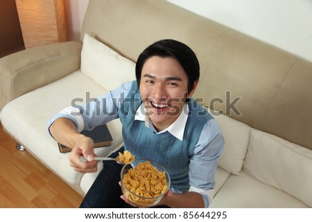 Smiling man eating a bowl of cereals