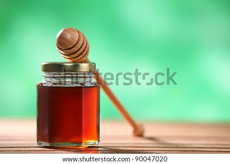 honey muddler resting on top bottle of honey