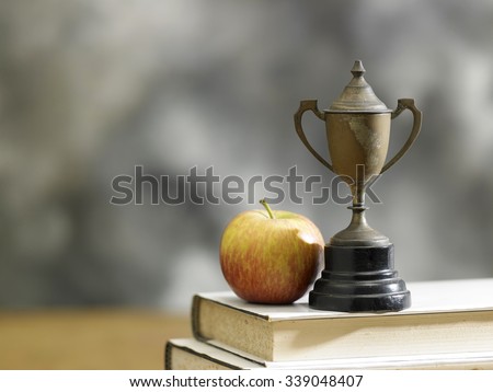 apple on a stack of books with a trophy