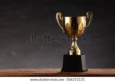 trophy on top of old wooden table in front of blackboard