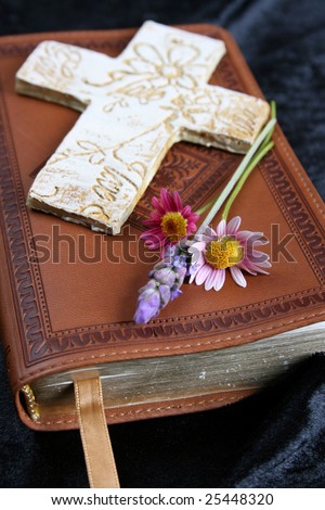 Ornate cross on a leather bound bible with flowers