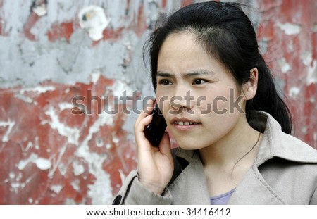Asian girl looking nervous talking on a cell phone