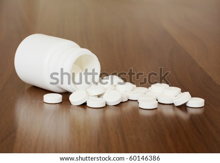 White pills spilling from a plastic bottle