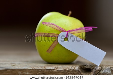 green apple with ribbon and blank white label