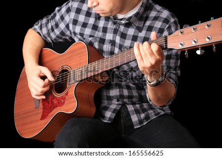 Young man playing guitar on a black background