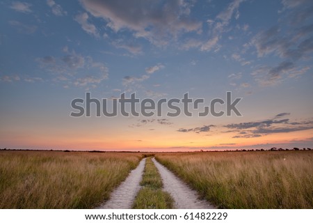 The sun sets over the Kalahari Pan with road leading towards the twilight