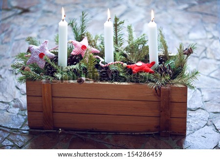 christmas decoration: Burning candles in a wooden box with fir branches and Christmas fabric toys