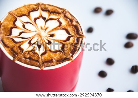 A latte art in red coffee cup with seeds coffee