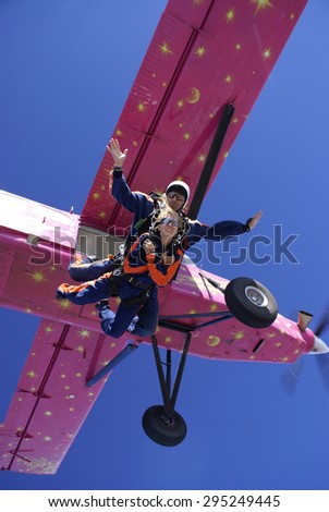 Tandem jump skydive with a parachute from a pink plane .