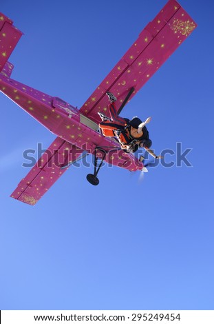 Tandem jump skydive with a parachute from a pink airplane .