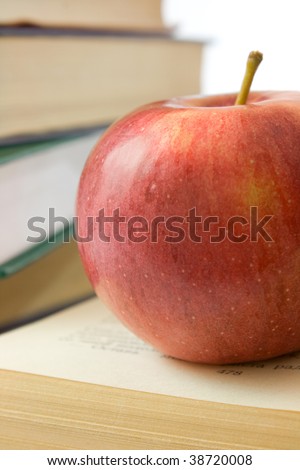 Red apple and pile of books. Photo close up.