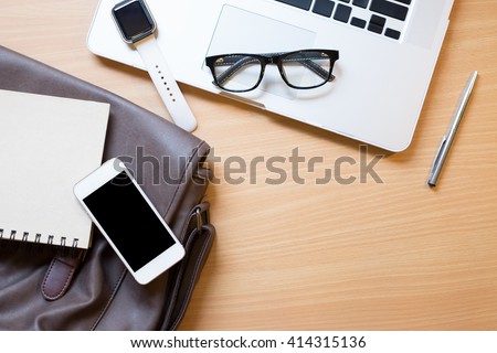 Business workplace from top smart watch, smart phone, glasses, laptop on wooden desk , retro style vintage tone