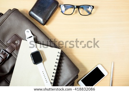 Business workplace from top smart watch, smart phone, glasses, laptop on wooden desk , retro style vintage tone