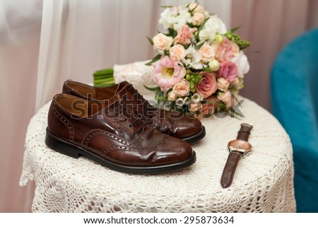 Man\'s groom shoes and watch near wedding bouquet