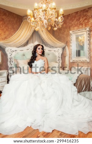 Beautiful woman bride in white wedding dress sitting in bedroom