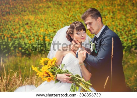 Wedding couple in the summer field with sunflowers bouquet