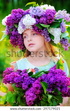 Portrait of a little girl with a bouquet of lilacs teenager in his hand and a wreath of flowers of lilac color . Serious facial expression. Shooting was conducted outdoors in the evening.