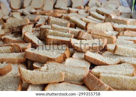 A lot of the cut slices of bread dry on a table. Preparation of house crackers.