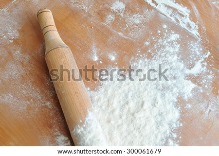 The kitchen table while cooking. Spilling the flour with a rolling pin on the kitchen table . Side light. Cooking pizza or cake. Free space for text .