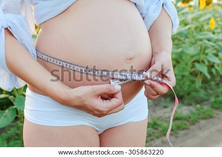 The young pregnant girl measures the volume of a stomach