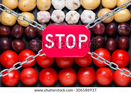 Chain and a \'stop\' sign on a vegetables background, in context of sanctions and extermination of food in Russia