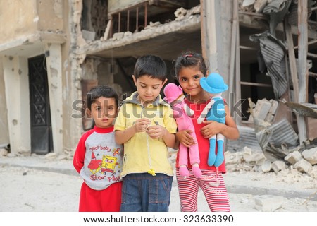 Homs, Syria, September 2013. Children play among the destroyed house in a district of the city of Homs. Several areas of the city of Homs were the scene of fighting between the Syrian army and rebels.