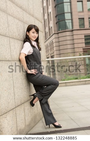 Confident business woman lean against wall in city.