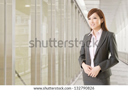Confident Asian business woman stand in front of office buildings.