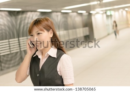 Portrait of young business woman stand and talk on mobile phone in the MRT station, Taipei, Taiwan, Asia.
