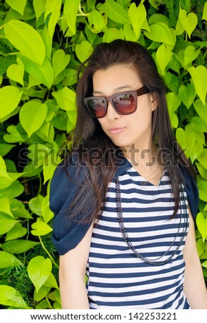 Asian attractive young woman against green plant wall, closeup portrait.