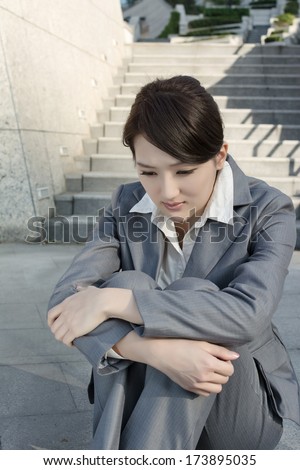 Sad business woman feel helpless and sit on stairs in modern city.