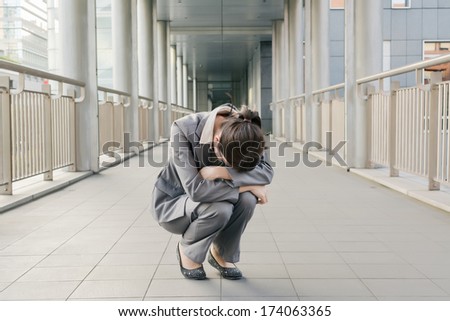 Business woman feel helpless and sadness and squat on ground in city.