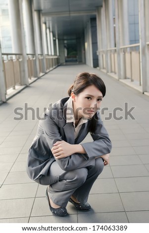 Business woman feel sad and squat on ground look at you in city.
