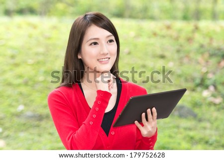Attractive young Asian woman using pad, closeup portrait.