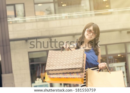 Fashion lady of Asian holding shopping bags in modern city.